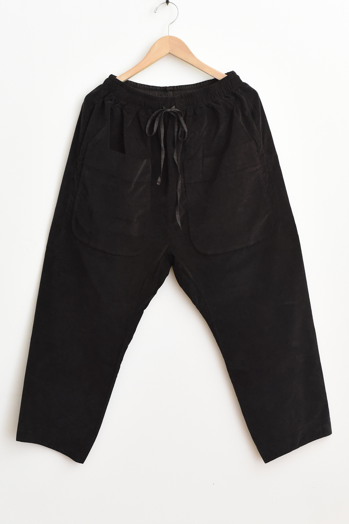 Album di Famiglia U23126 Braghe Tasche Velvet pants in brown, featuring large front pockets and a drawstring waist, hanging on a wooden hanger against a white background.