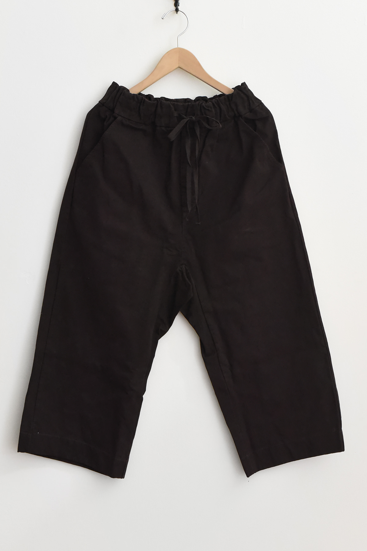 Album di Famiglia 23269 Wide & Short Trousers WCC in brown, featuring an elastic waistband and drawstring, displayed on a wooden hanger against a plain white background.